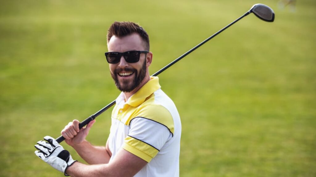 Golfer mit Sonnenbrille beim Abschlag auf dem Golfplatz
